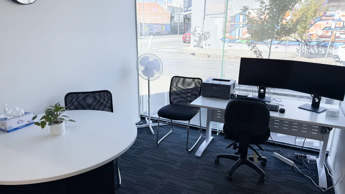 Appointment room with a round table and clinician desk beside a large window onto Sydney Road at ORS Coburg