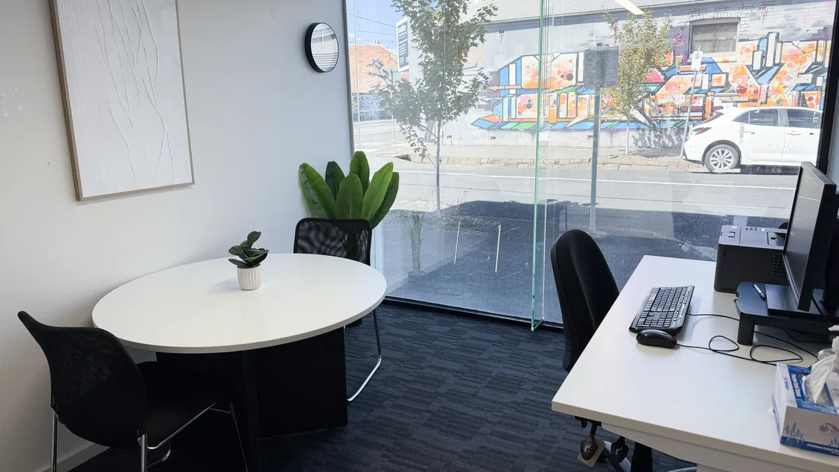 Consulting room with a round meeting table, clinician workstation and indoor plant at ORS Coburg