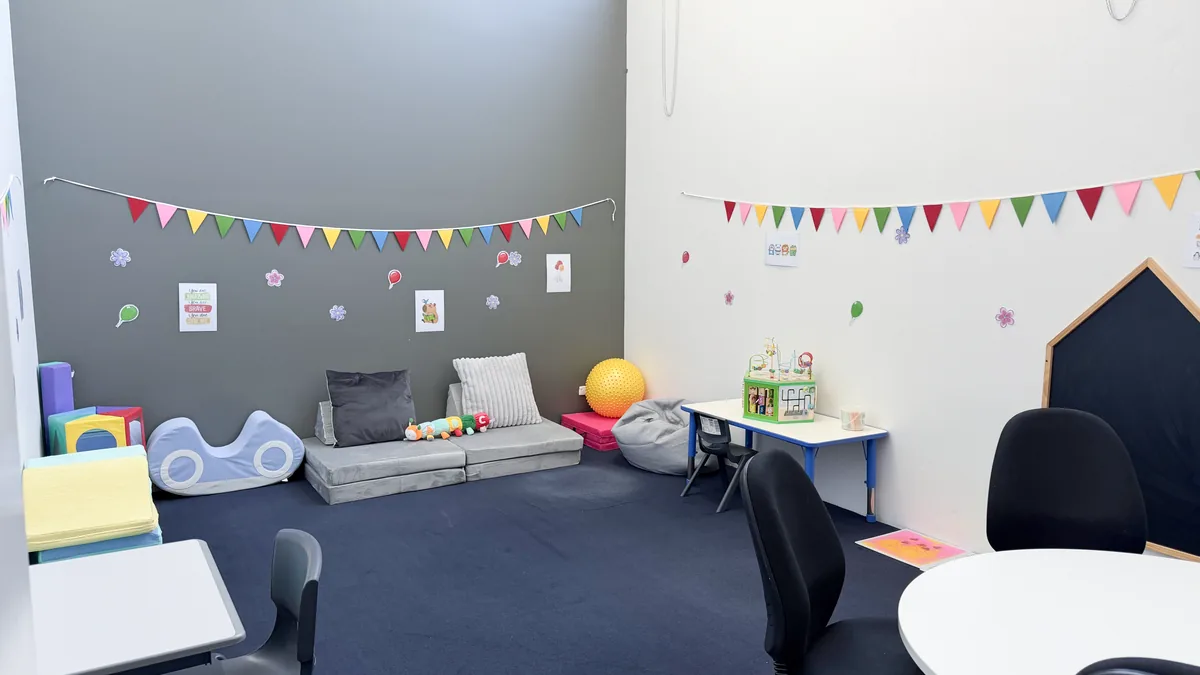 Paediatric therapy room with soft play mats, a play corner, bunting and child-sized furniture at ORS Coburg