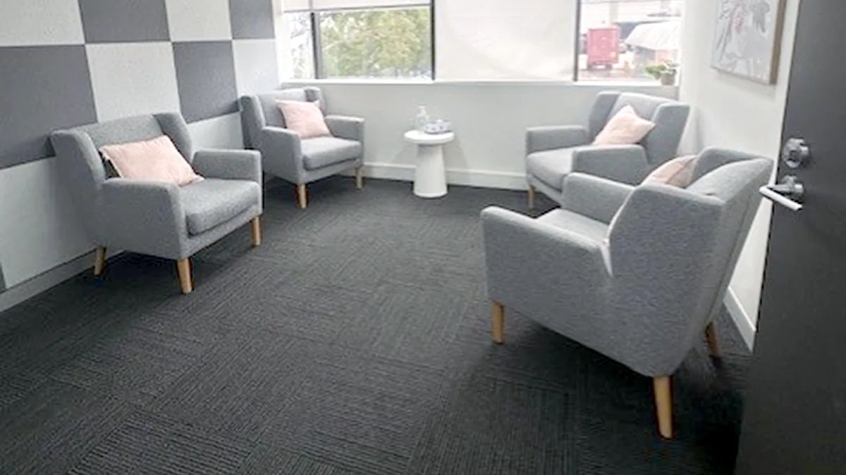 Wheelchair accessible counselling room with grey armchairs, pink cushions and a feature wall at ORS Fairfield East