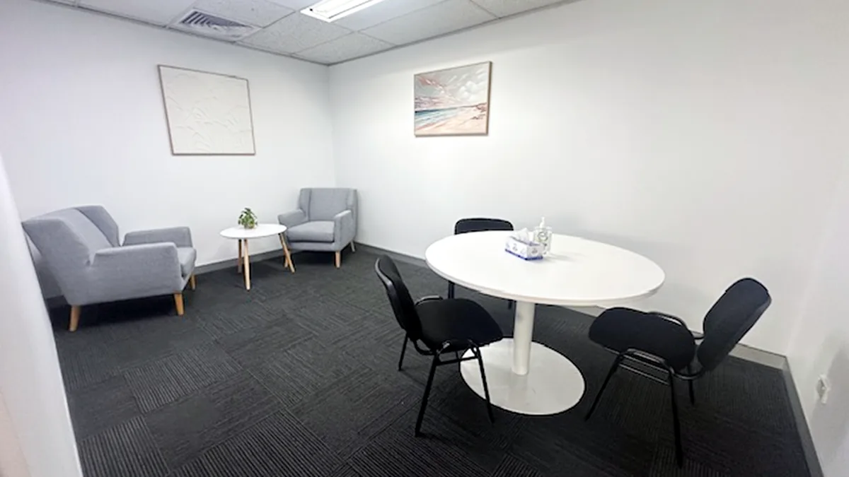 Counselling and appointment room with two armchairs, a side table and a round meeting table at ORS Fairfield East