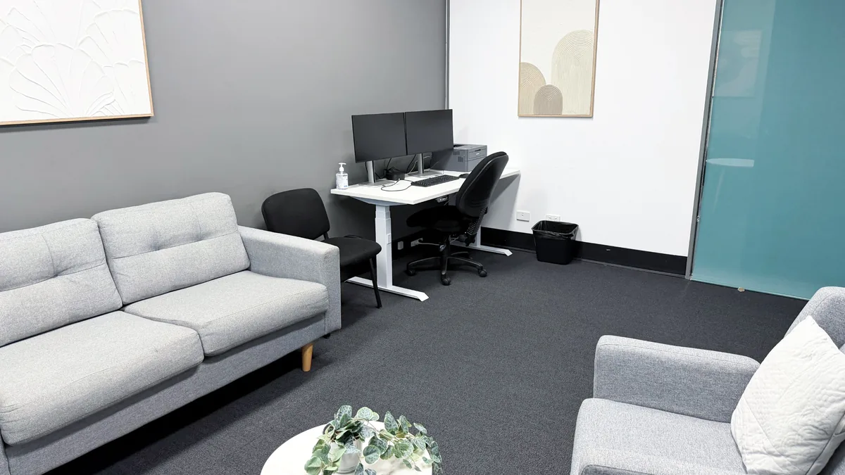 Consult and counselling room with grey armchairs, a lounge and a garden-facing window at ORS Fyshwick
