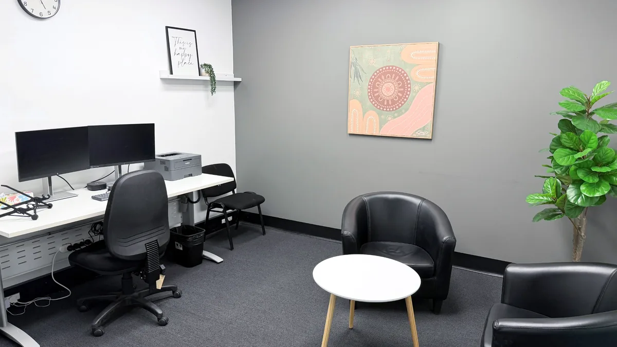 Consulting room with leather tub chairs, a round coffee table and a clinician desk at ORS Fyshwick