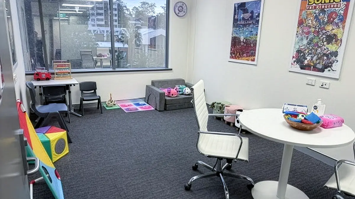 Paediatric therapy room with a play corner, colourful wall posters and a round consultation table at ORS Gosford