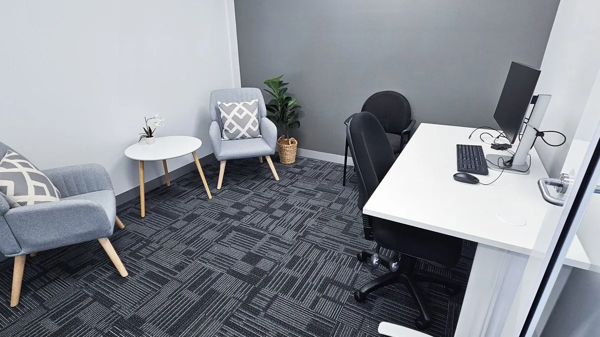 Counselling room with two armchairs, a side table and clinician desk at ORS Joondalup