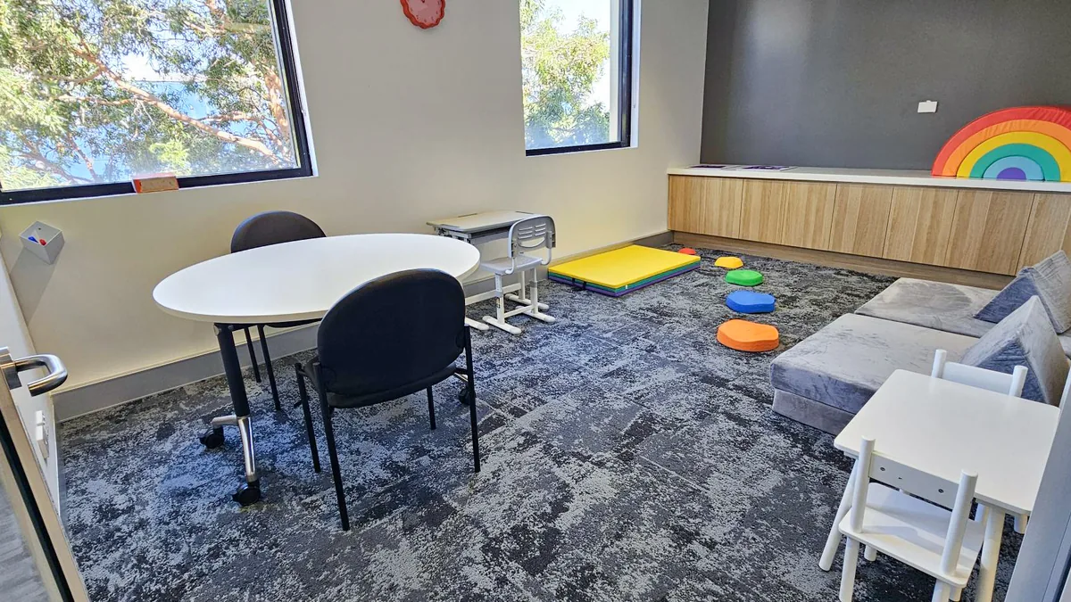 Paediatric therapy room with a rainbow stacker, soft play lounge, stepping stones and round table at ORS Joondalup