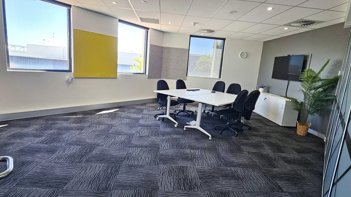 Training and assessment room with meeting tables, chairs, a wall-mounted screen and large windows at ORS Joondalup