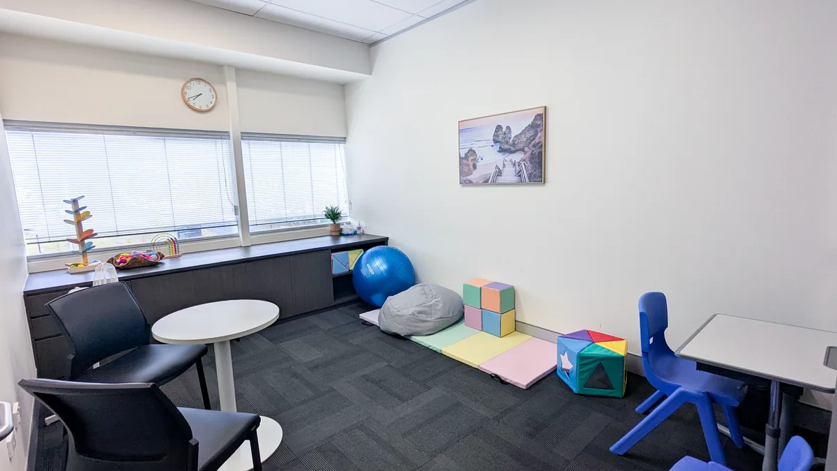 Paediatric appointment room with child-sized chairs, a play mat, a round table and toys at ORS Mitchell