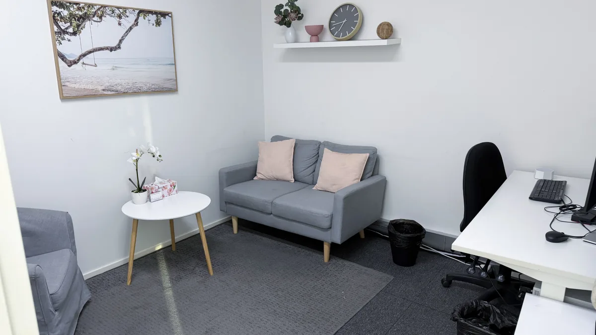Accessible counselling room with a grey two-seater lounge, pink cushions and side table at ORS Morley