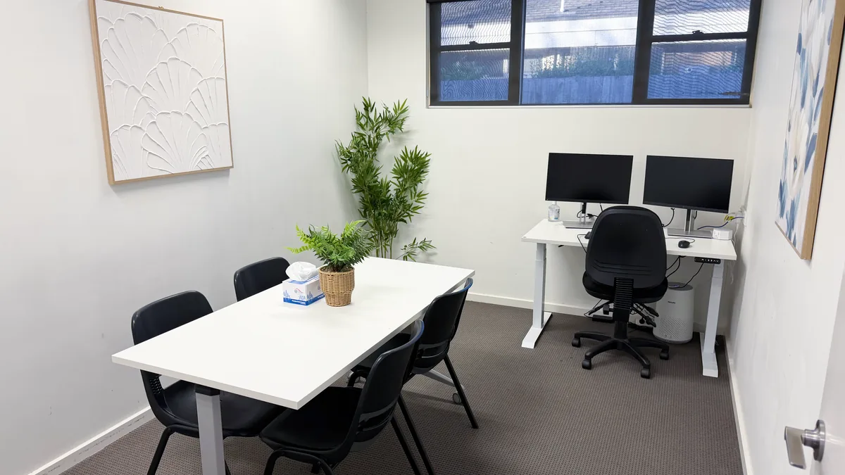 Assessment room with a meeting table, chairs, clinician desk and window at ORS Pakenham