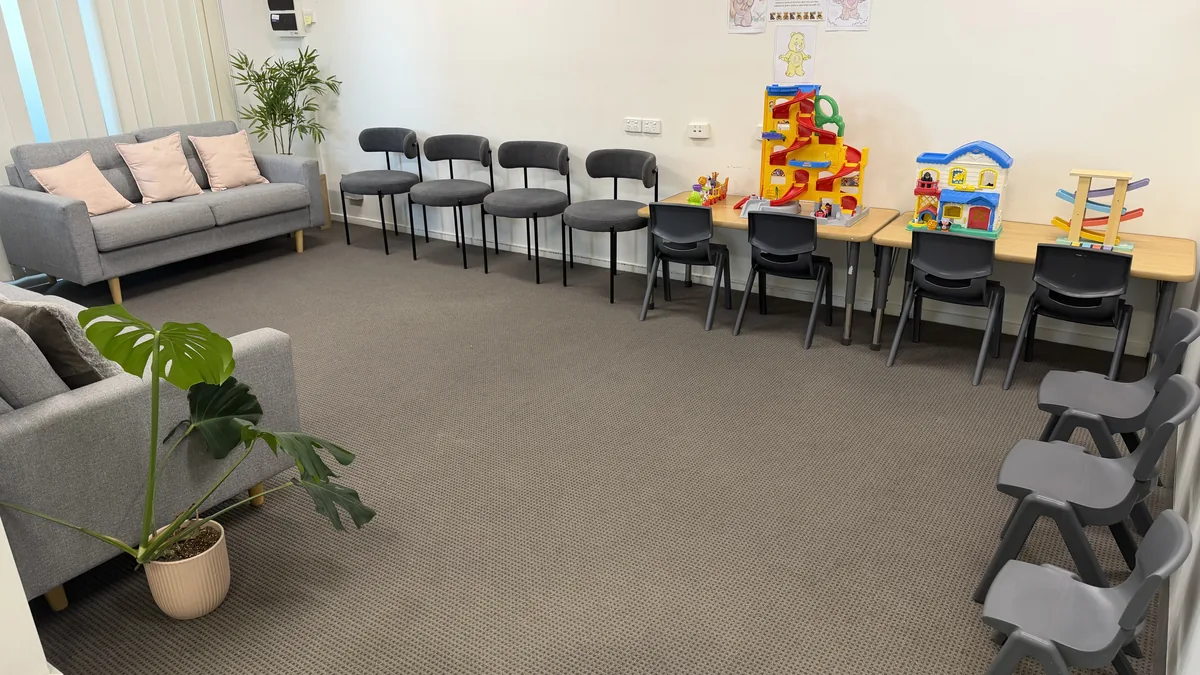 Client waiting area with lounges, pink cushions, seating and a children's play table with toys at ORS Pakenham