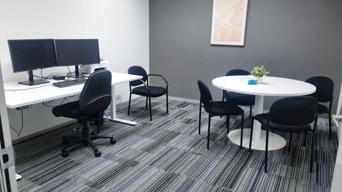 Consulting room with a round meeting table, chairs and a clinician workstation at ORS Stirling