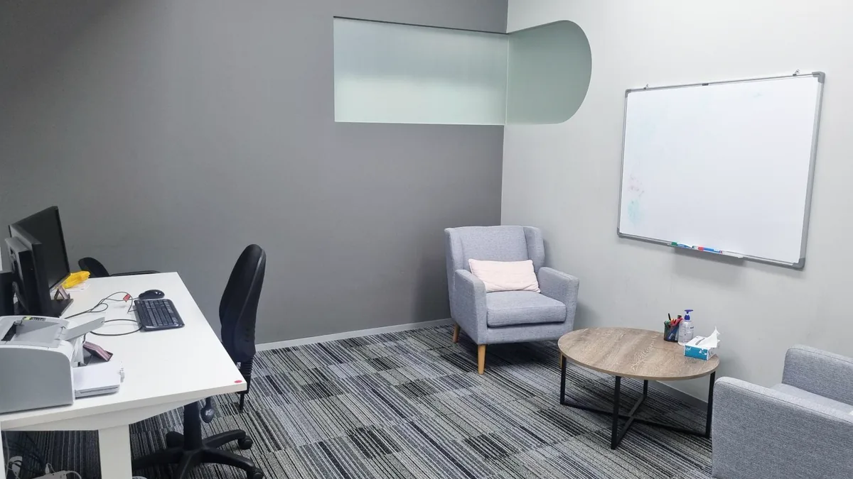 Counselling room with an armchair, a lounge, a round coffee table and whiteboard at ORS Stirling