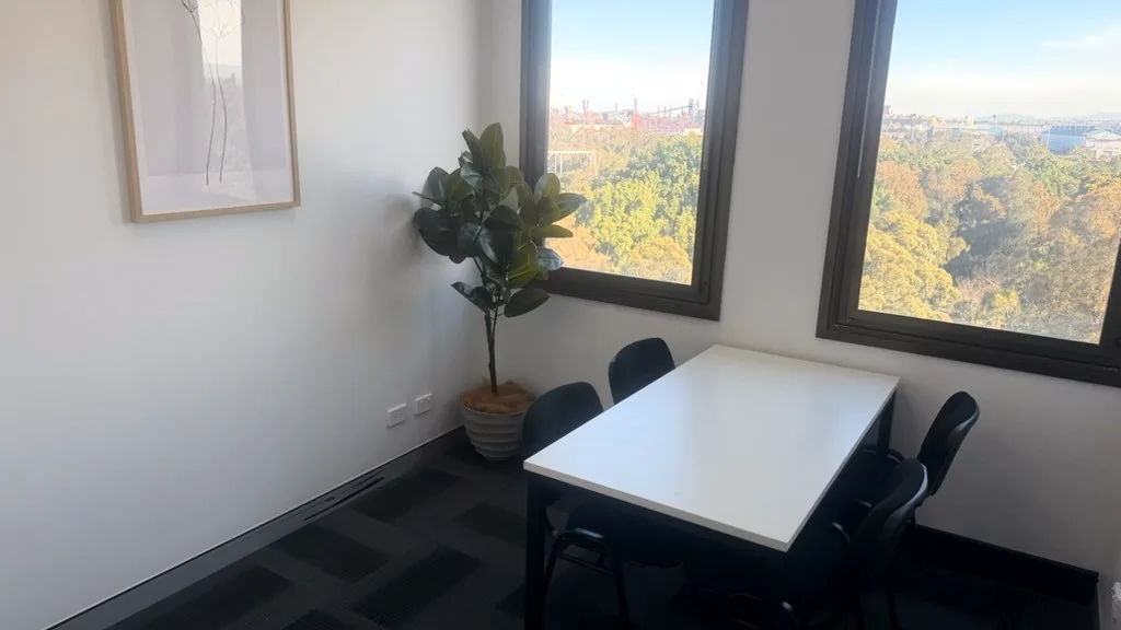 Consulting and assessment room with a table, chairs and treetop views through two windows at ORS Wollongong