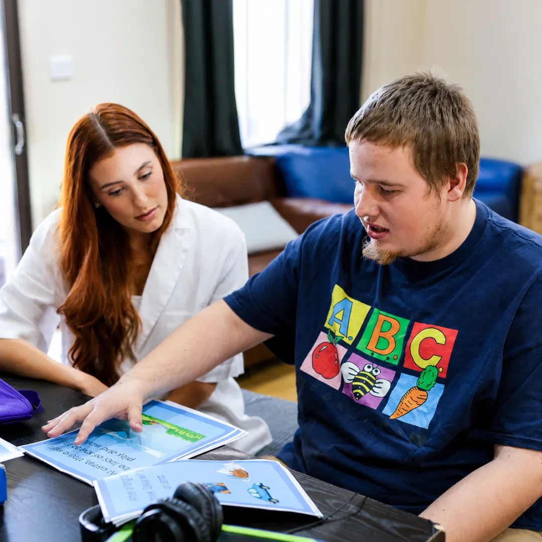 Positive Behaviour Support practitioner working with an adult NDIS participant using visual resources to build everyday skills and independence.