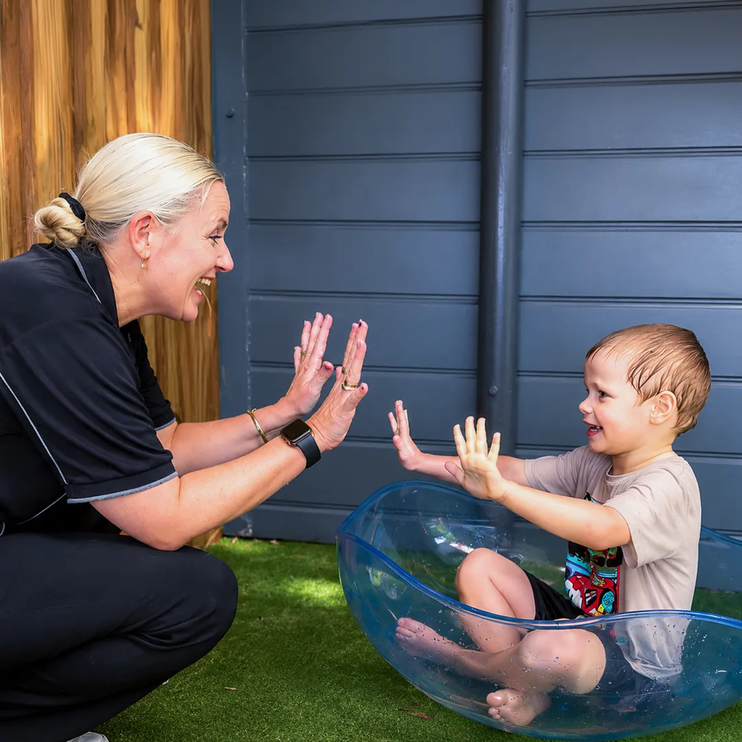 Positive Behaviour Support practitioner using play-based strategies with a young child during an NDIS therapy session.